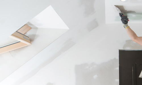 A drywalled ceiling getting spackled applied to it.