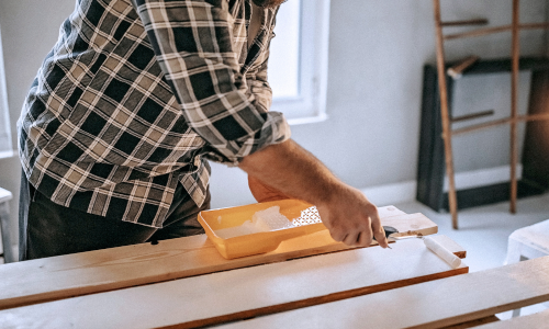 Boards of lumber being painted white with a small roller.