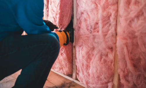Pink insulation being installed into a wall.