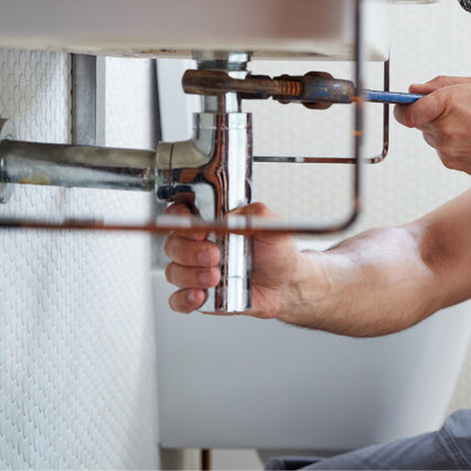 PlumbingA pipe underneath a sink being tightened by a wrench.